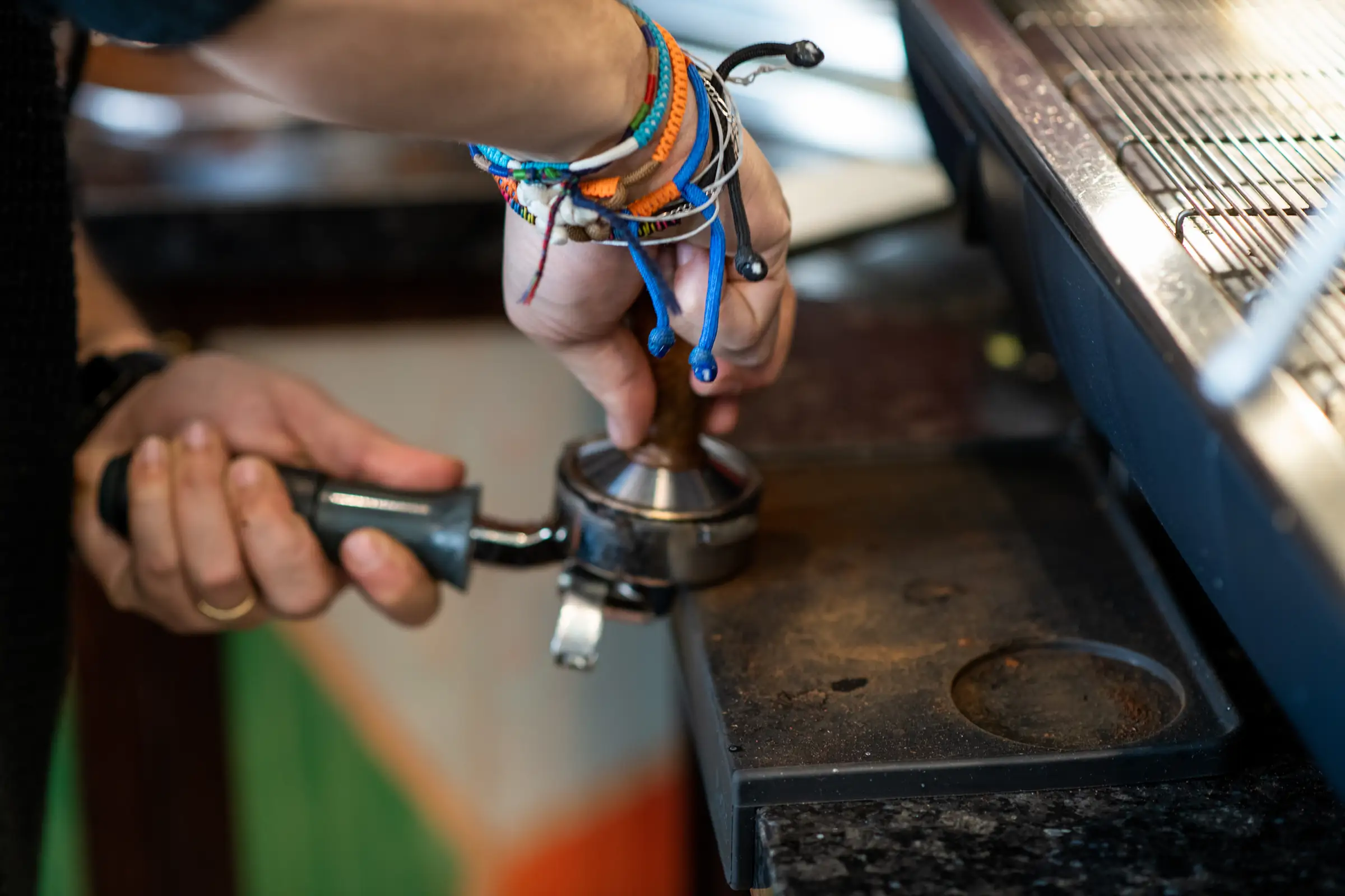Barista tamping ground coffee into a portafilter at the bar