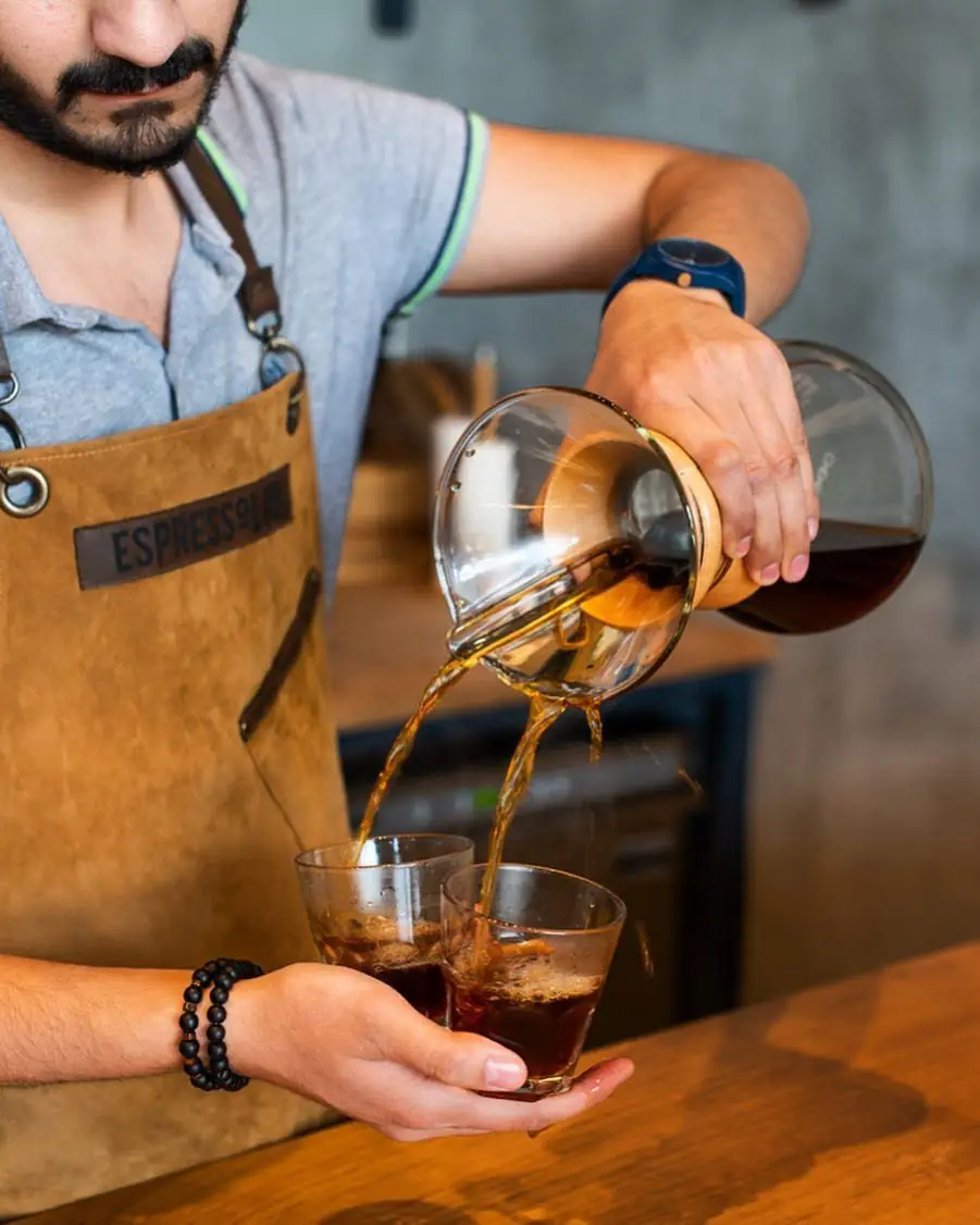 Bartender pouring a drink from a carafe into a glass across the bar