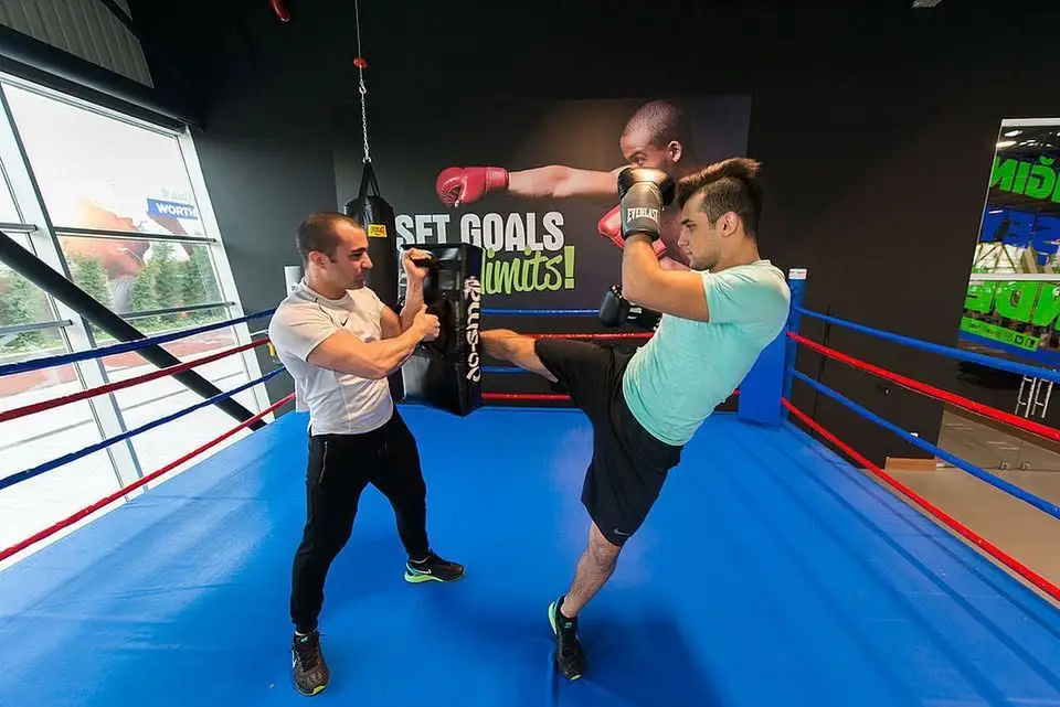 Trainer holding pads for a client in a boxing ring