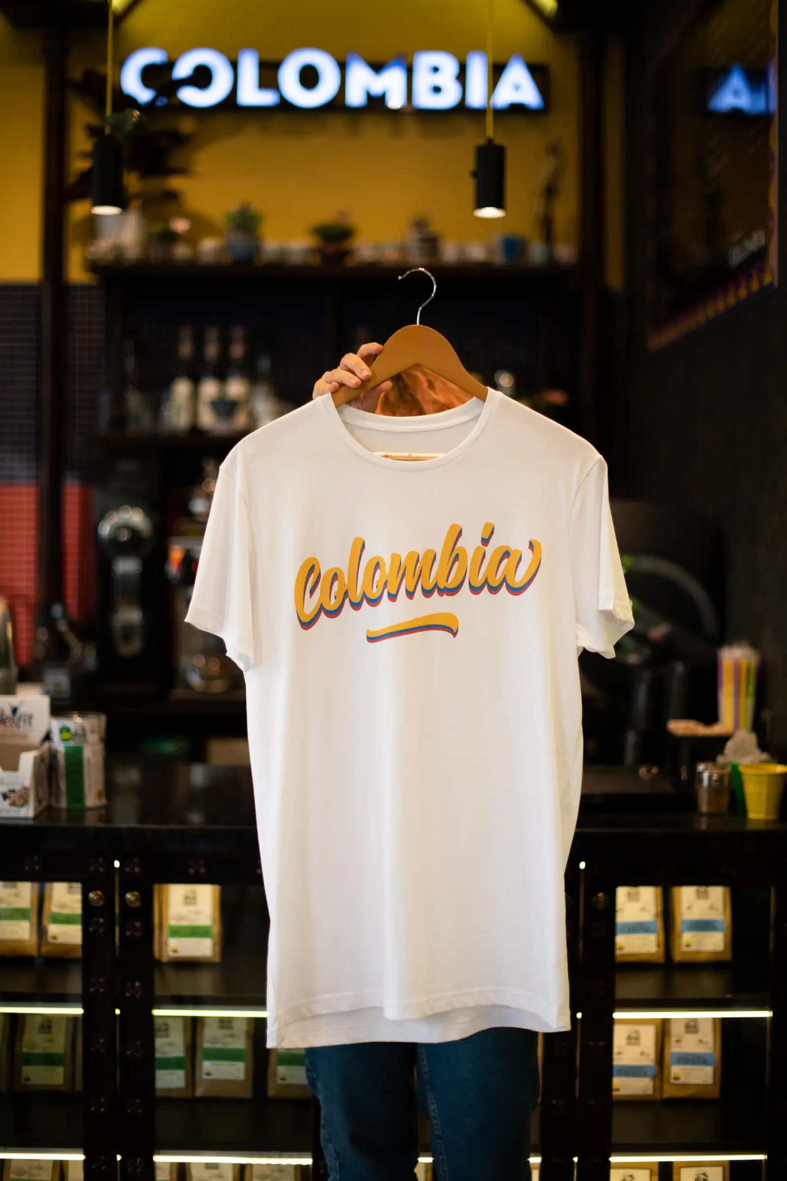 Printed cotton t-shirt held up on a hanger inside the coffee shop