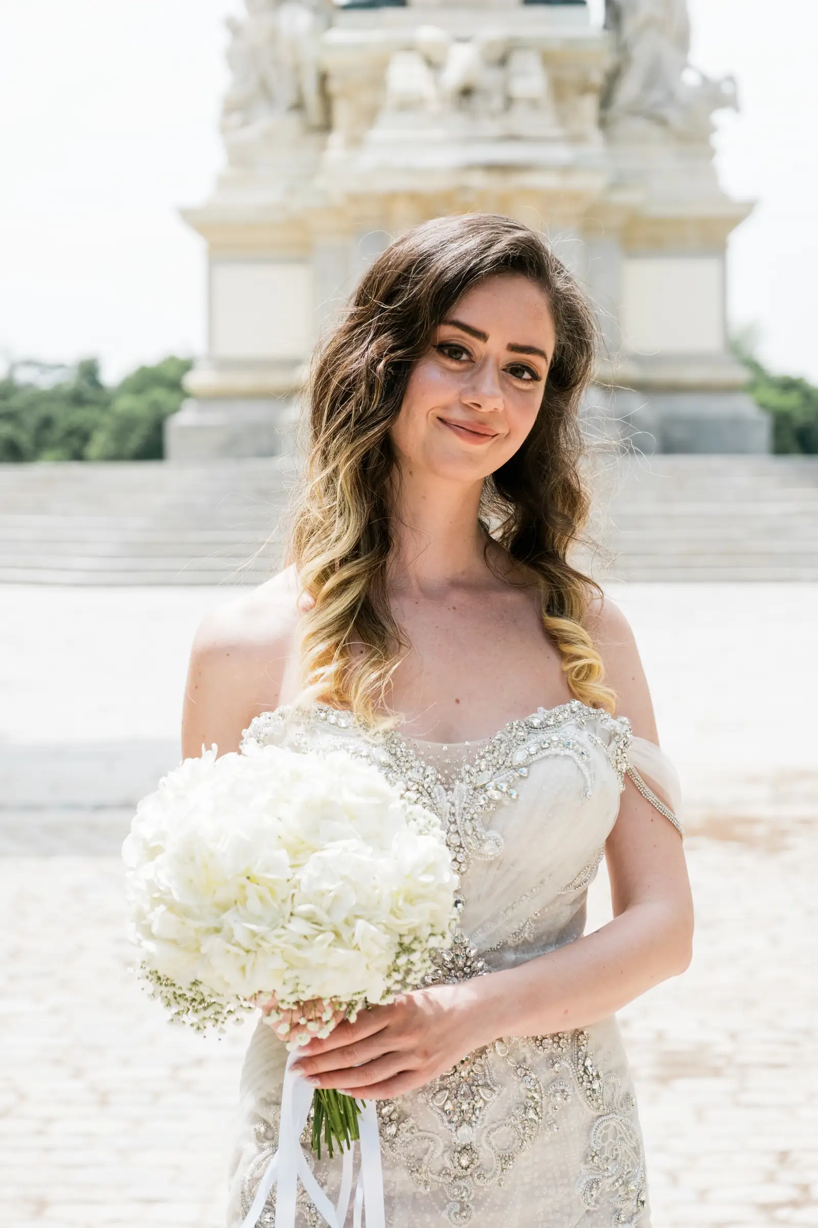 Bride holding a white hydrangea bouquet in front of the Alfonso XII monument in Madrid