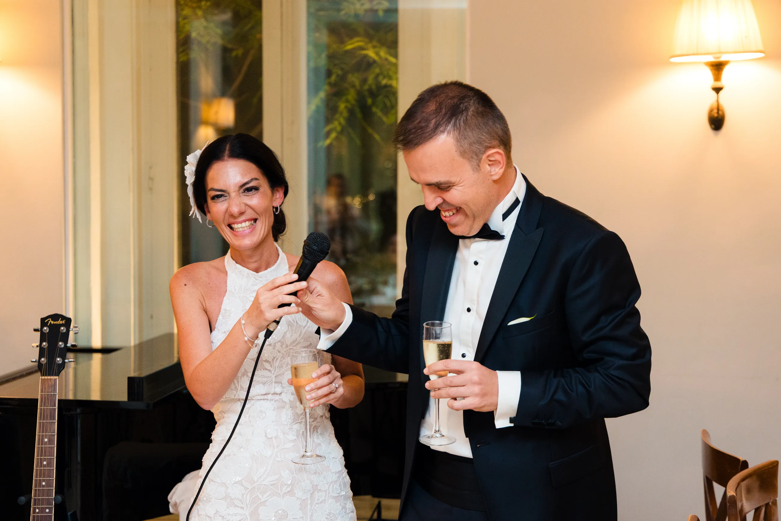 Bride and groom laughing during their toast with a microphone and champagne