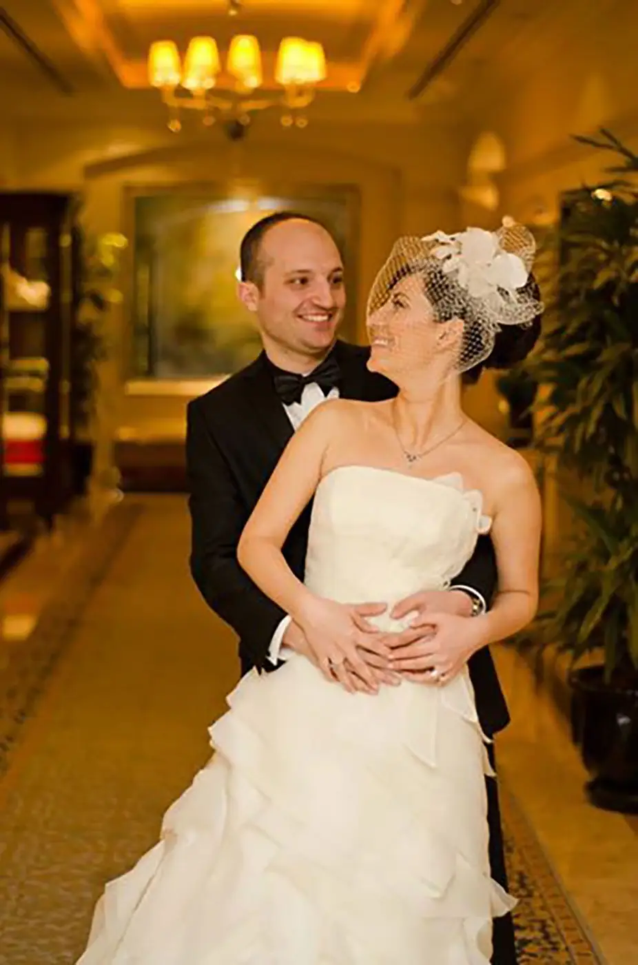 Bride laughing with her groom in a gold lit corridor