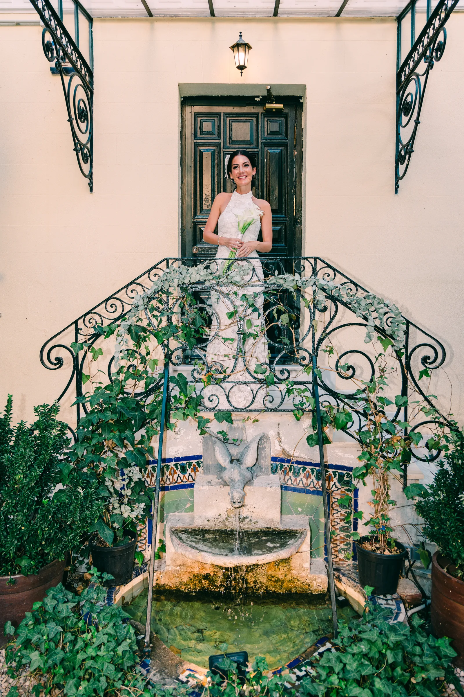 Bride at the top of an iron staircase above a tiled fountain courtyard
