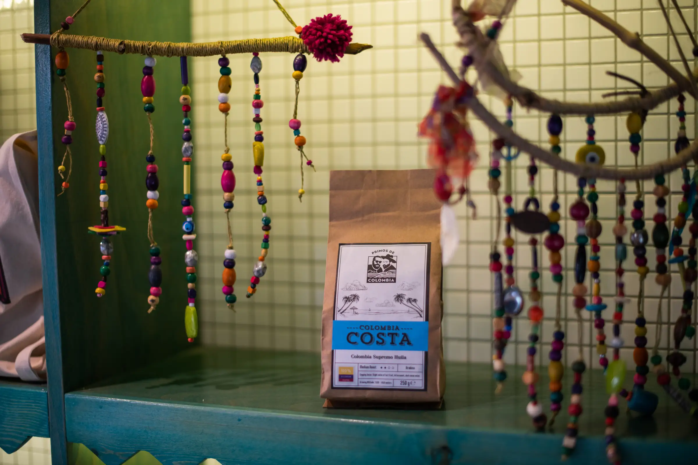 Bag of coffee styled on a shelf with hanging beaded decorations