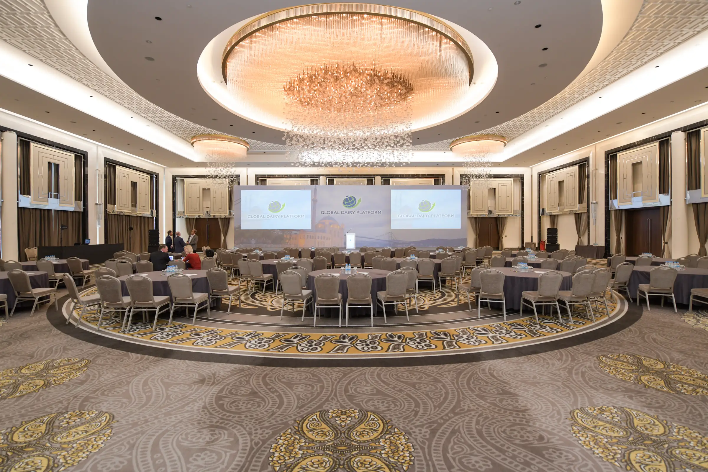 Hotel ballroom set with round tables and screens before a conference session