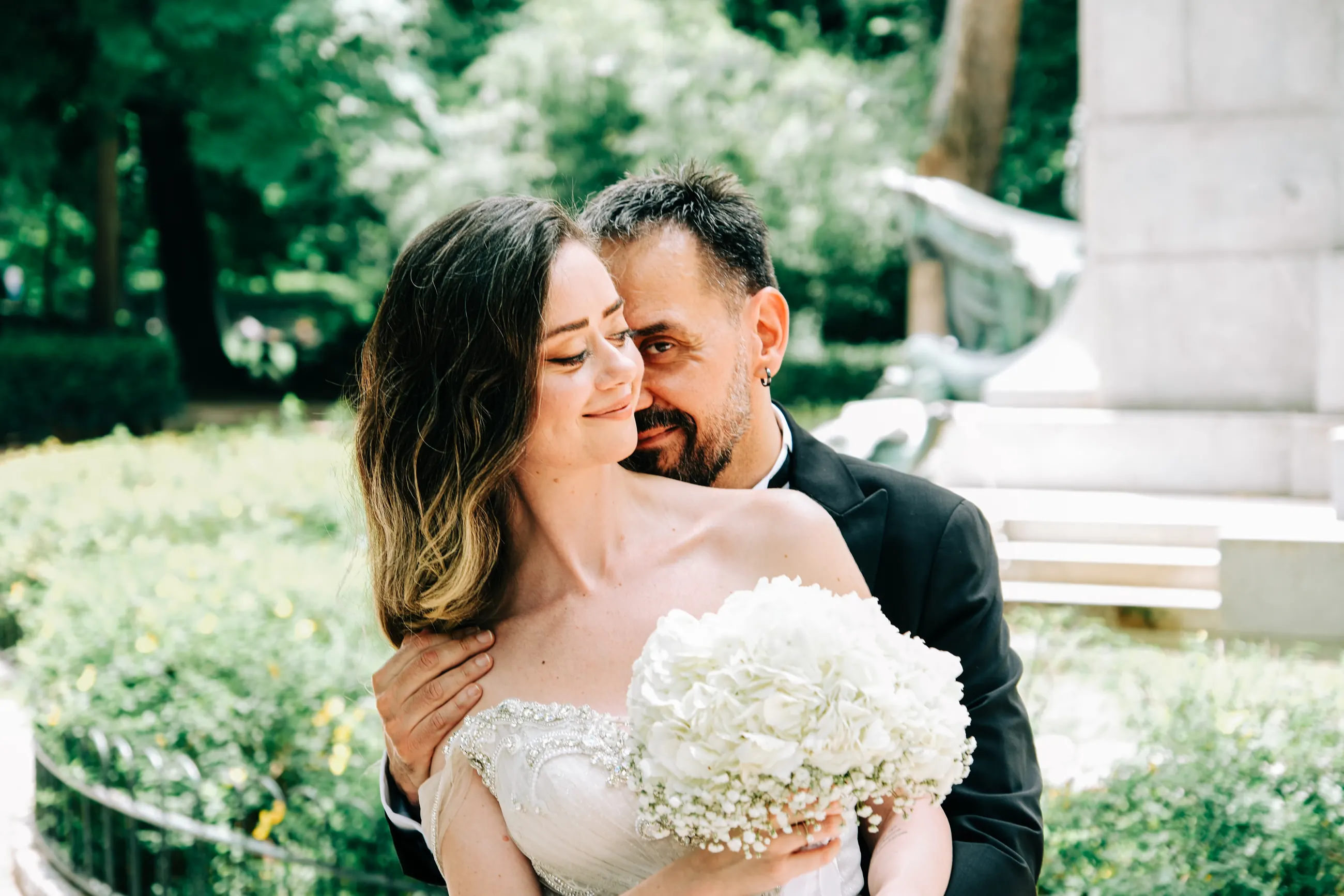 Couple embracing with eyes closed beside a fountain in a Madrid park