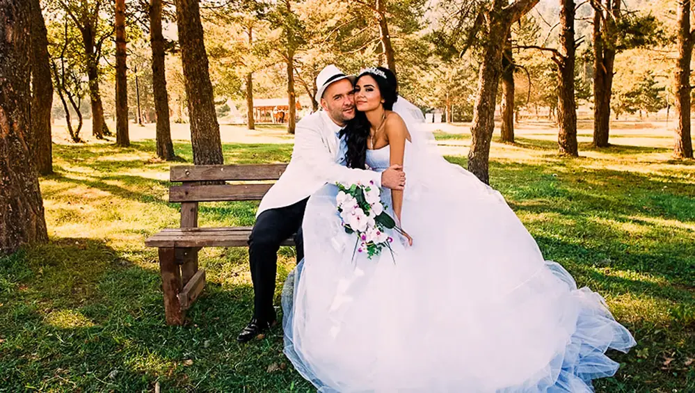 Couple embracing beside a wooden bench in an autumn park