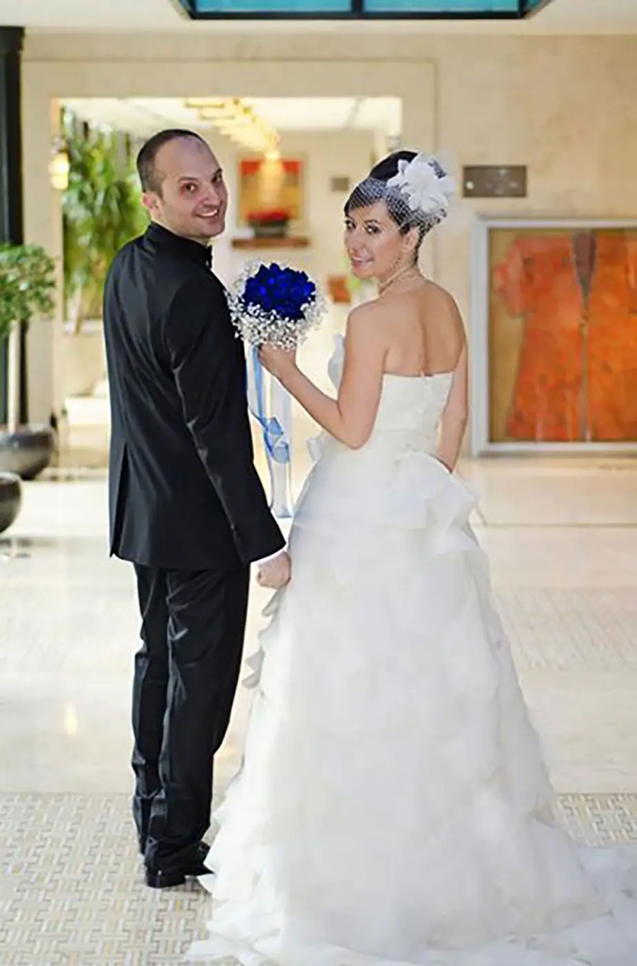 Bride and groom walking through a hotel atrium with a blue and white bouquet