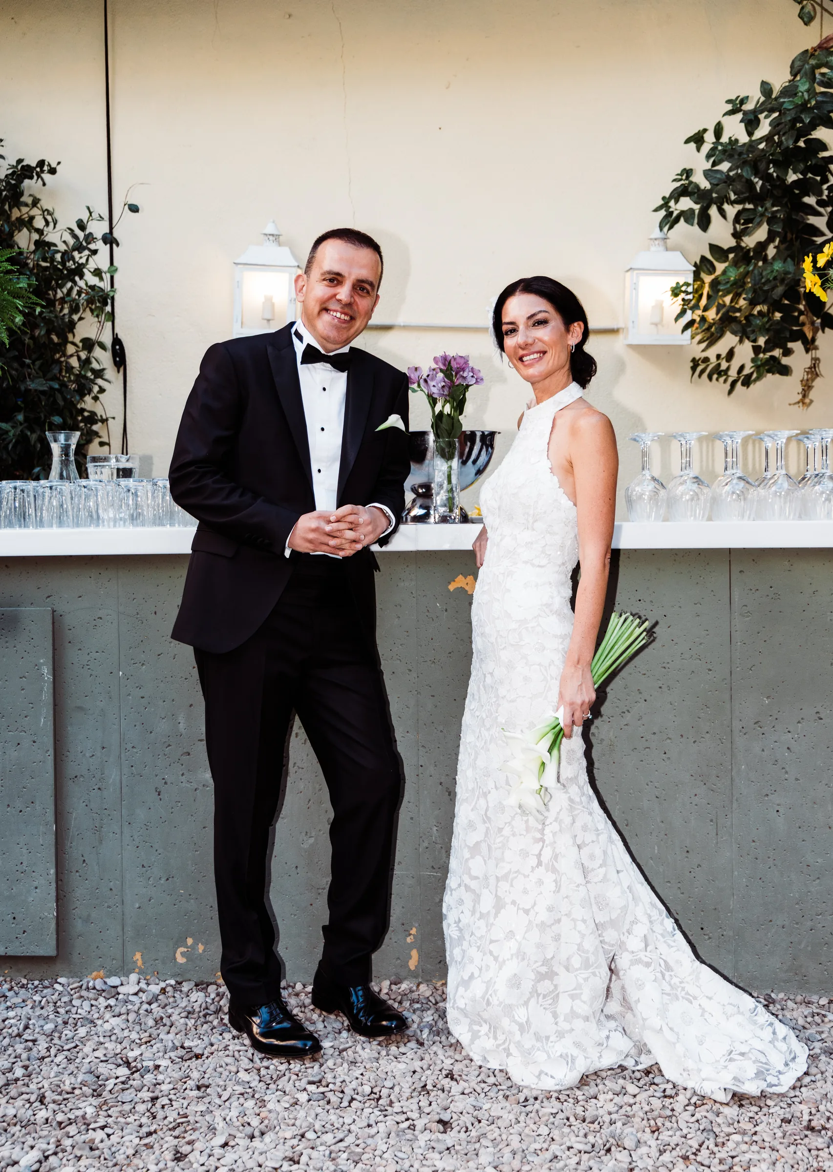 Couple standing by a terrace bar with flowers and glasses