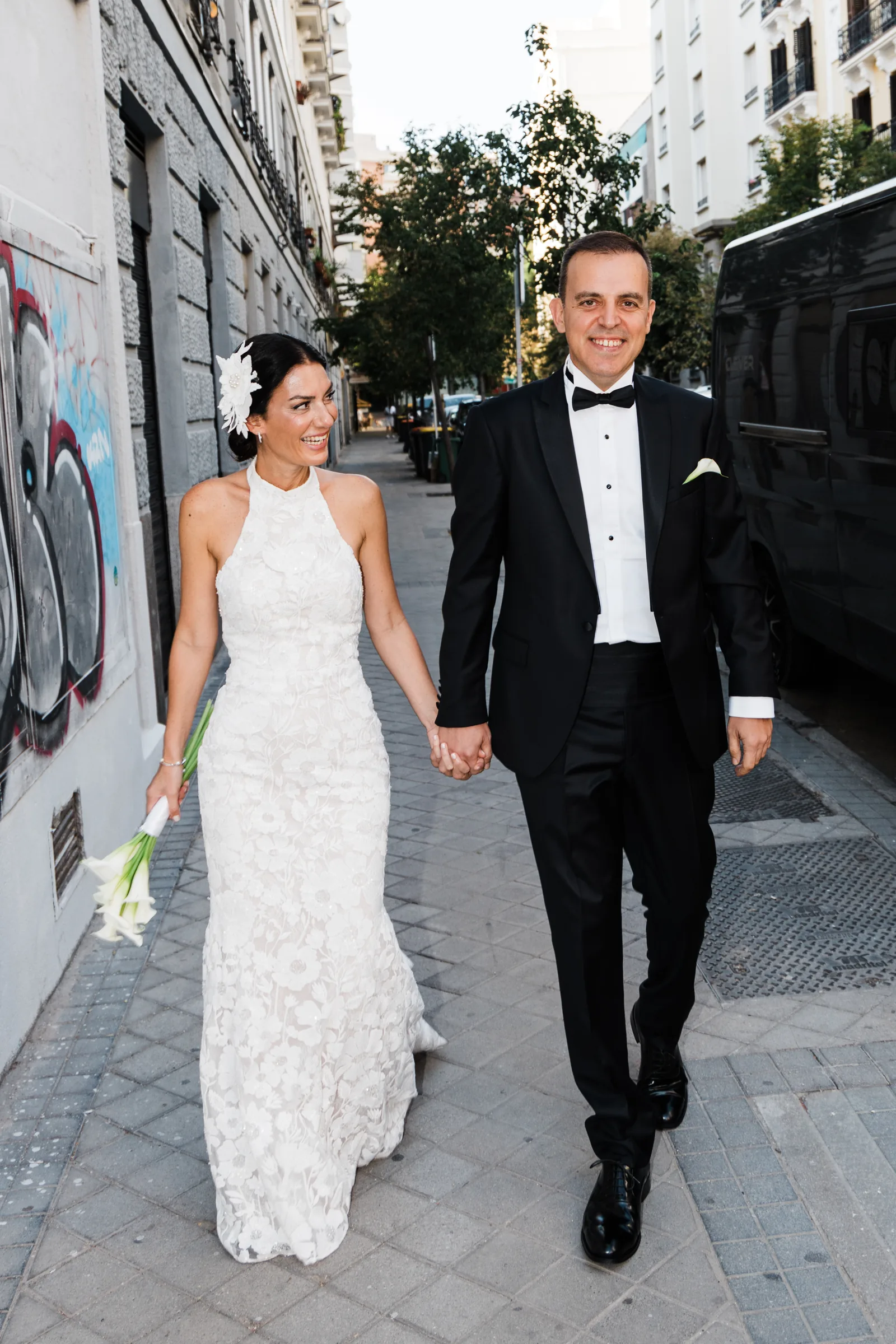 The bride and the groom walking hand in hand down a quiet Madrid street