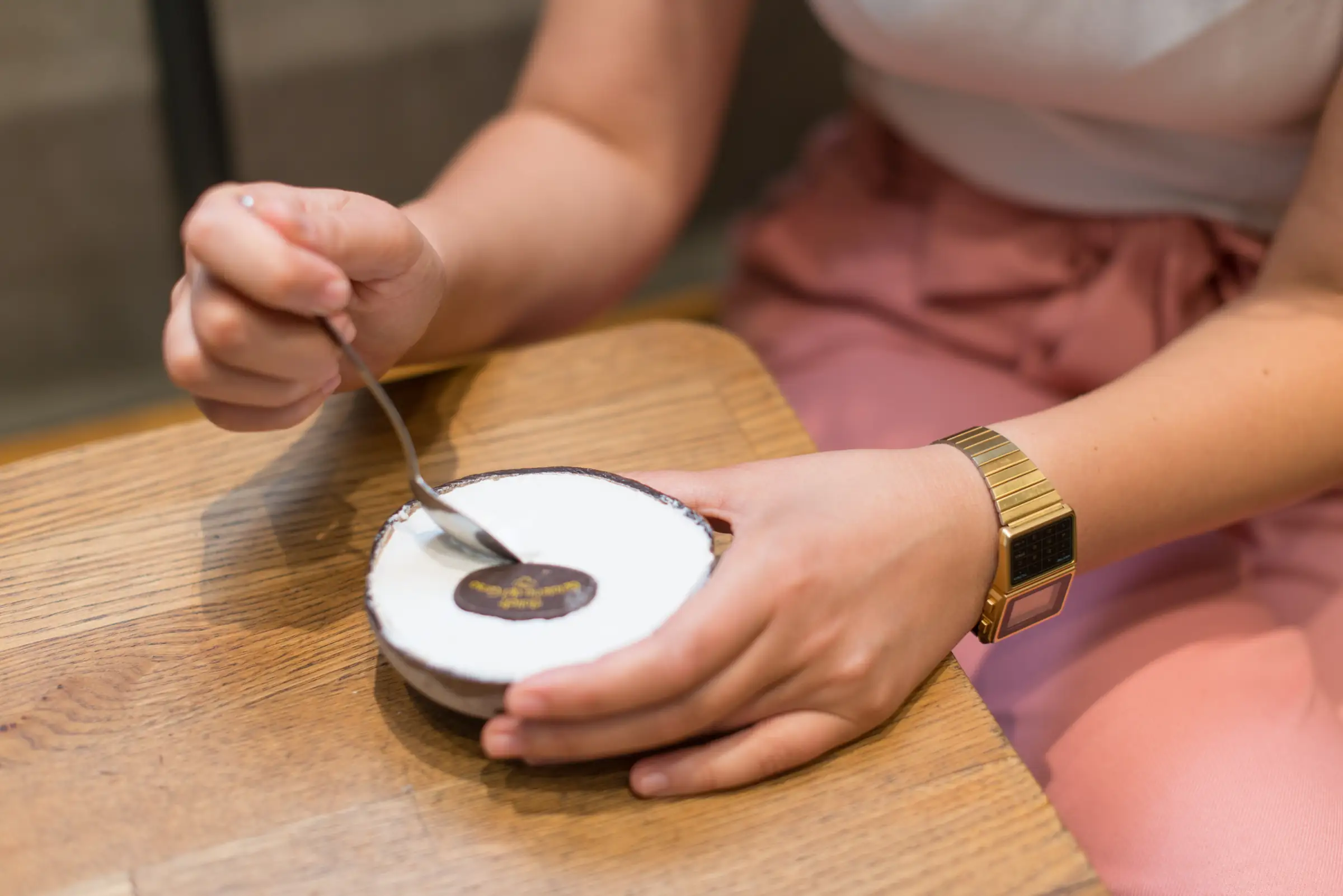 Hand lifting a spoon from a small chocolate dessert on a wooden board