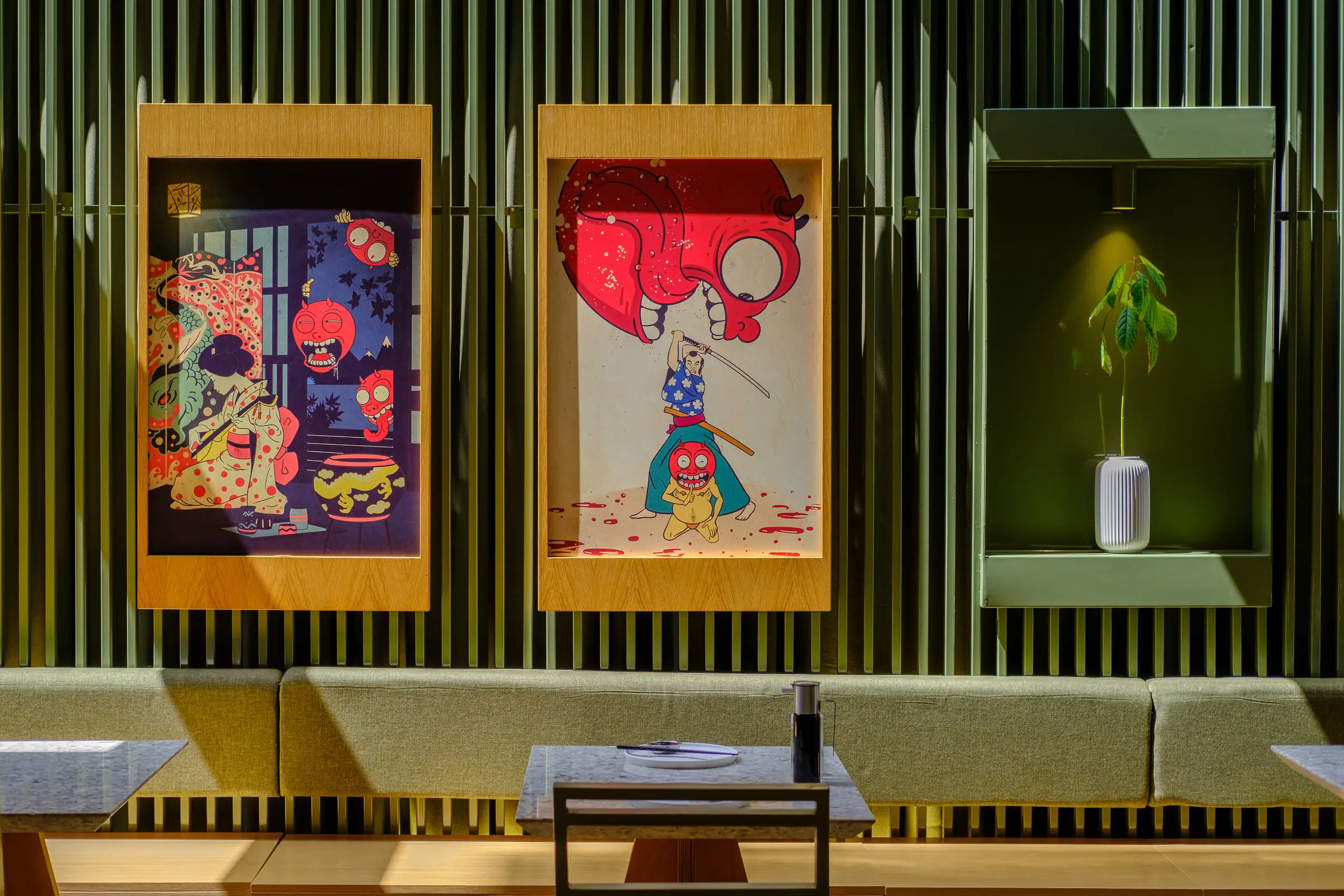 Framed Japanese prints above a laid table in a restaurant