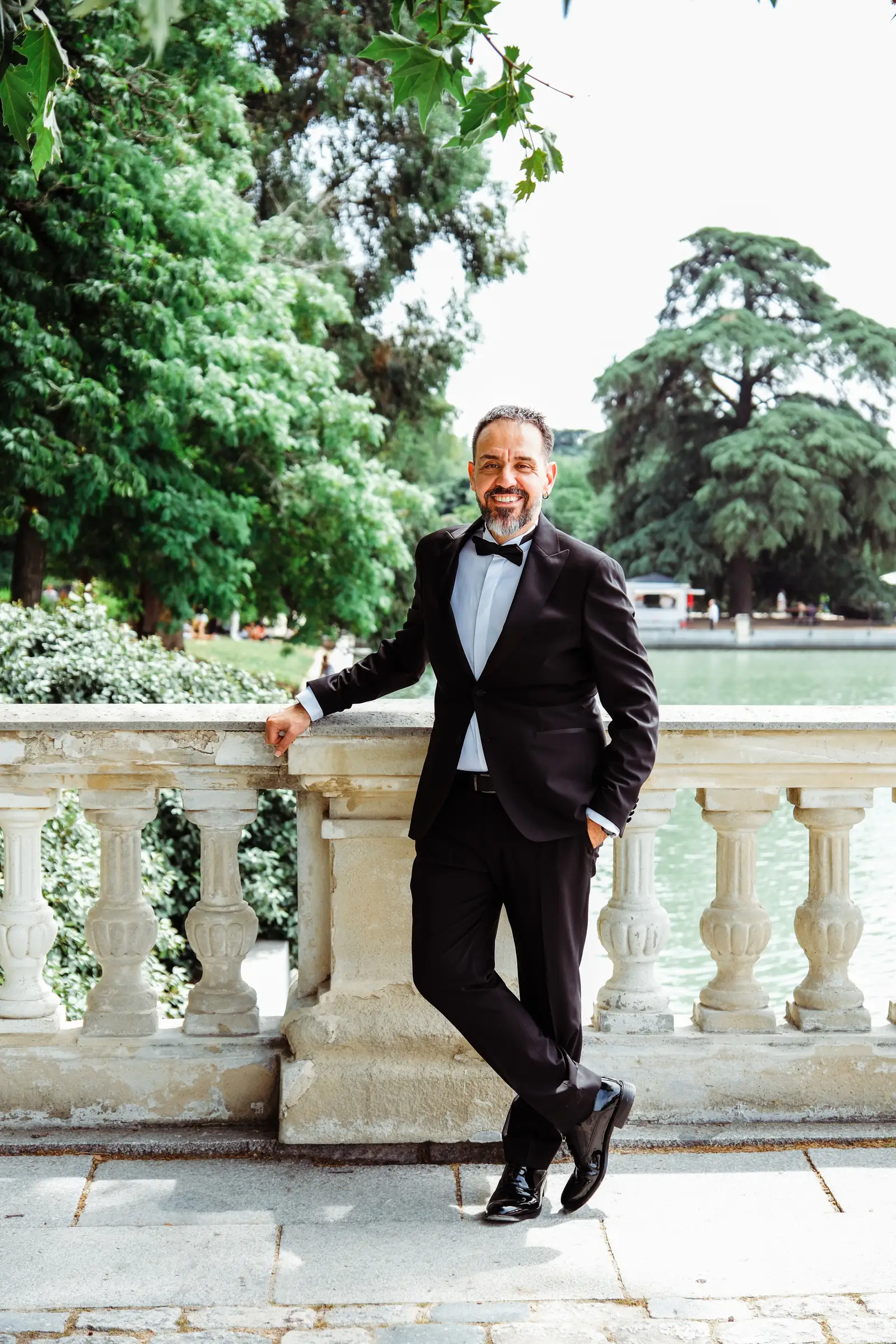 Groom leaning on the stone balustrade above the Retiro lake in Madrid