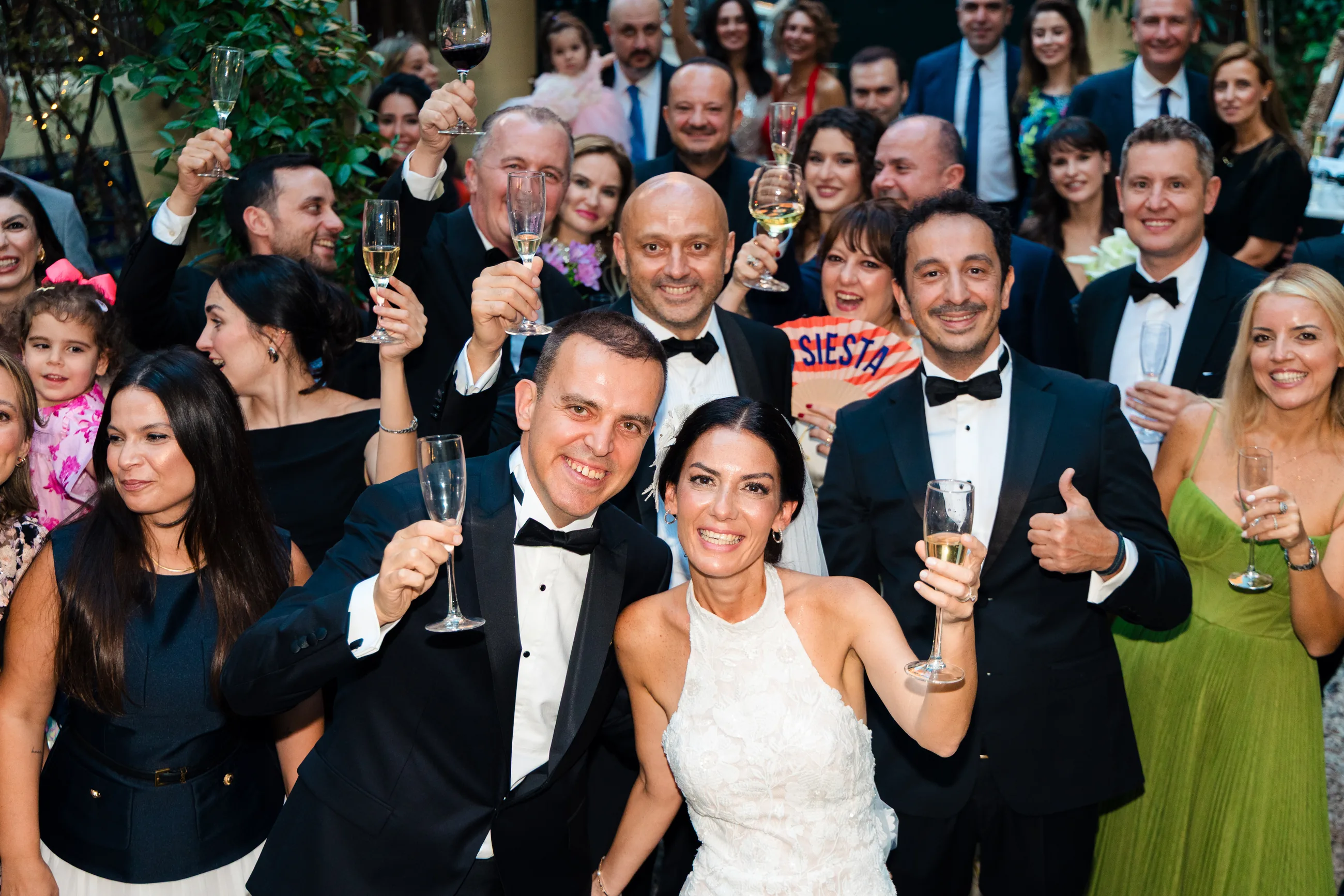 A large group raising champagne glasses at an outdoor celebration