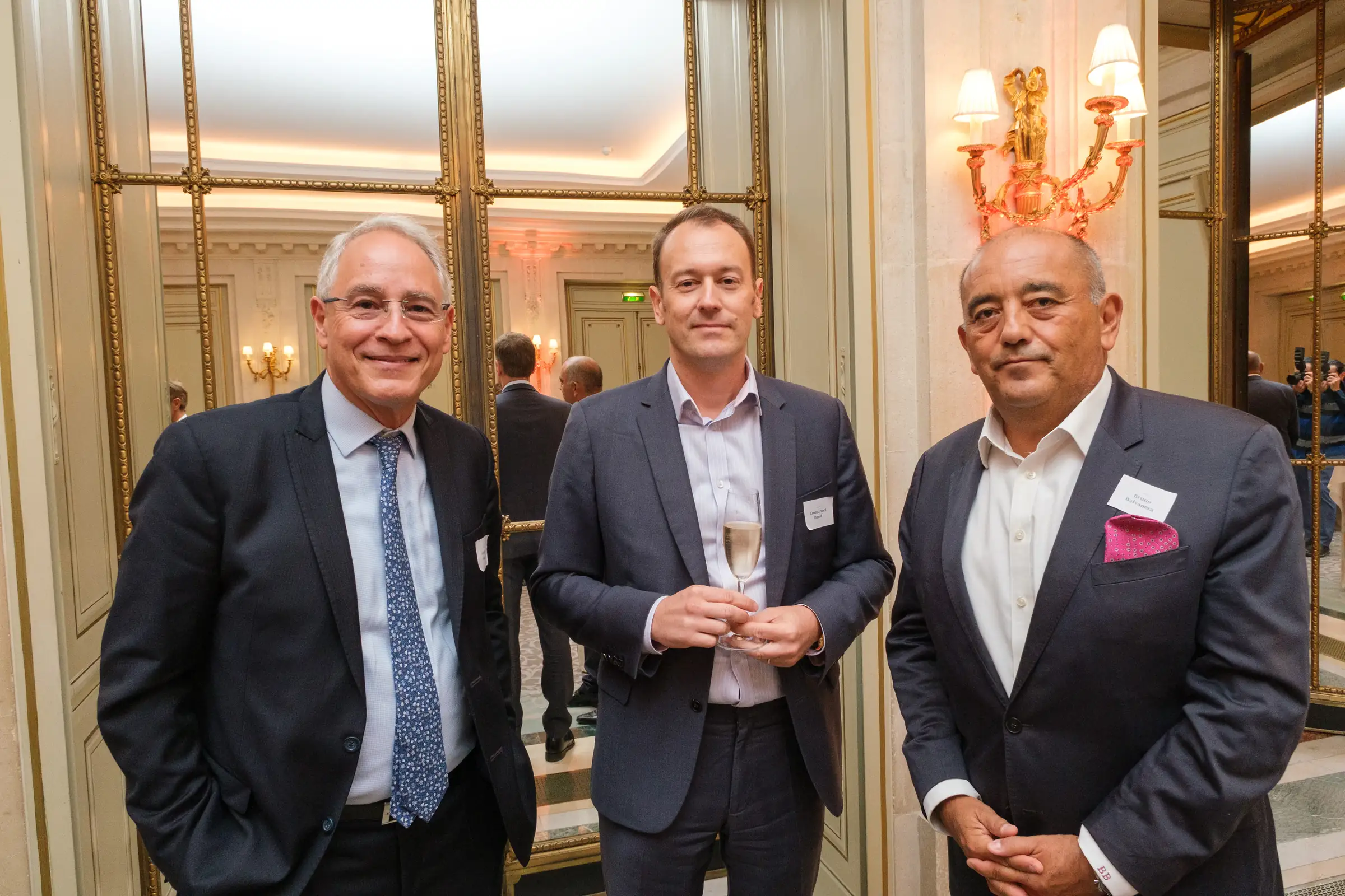 Three guests standing with drinks during a corporate reception
