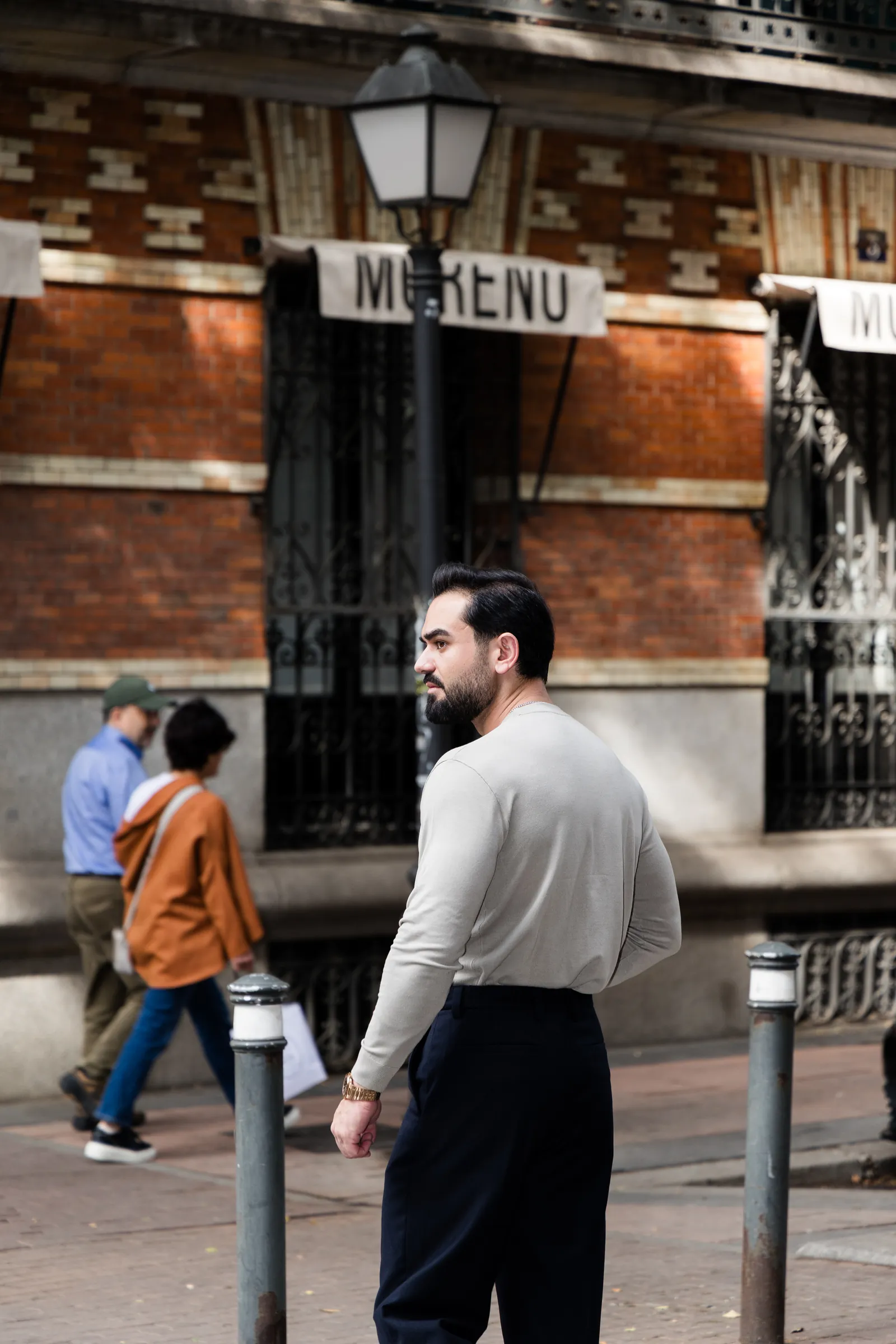 Man looking back over his shoulder as pedestrians pass on a brick lined street