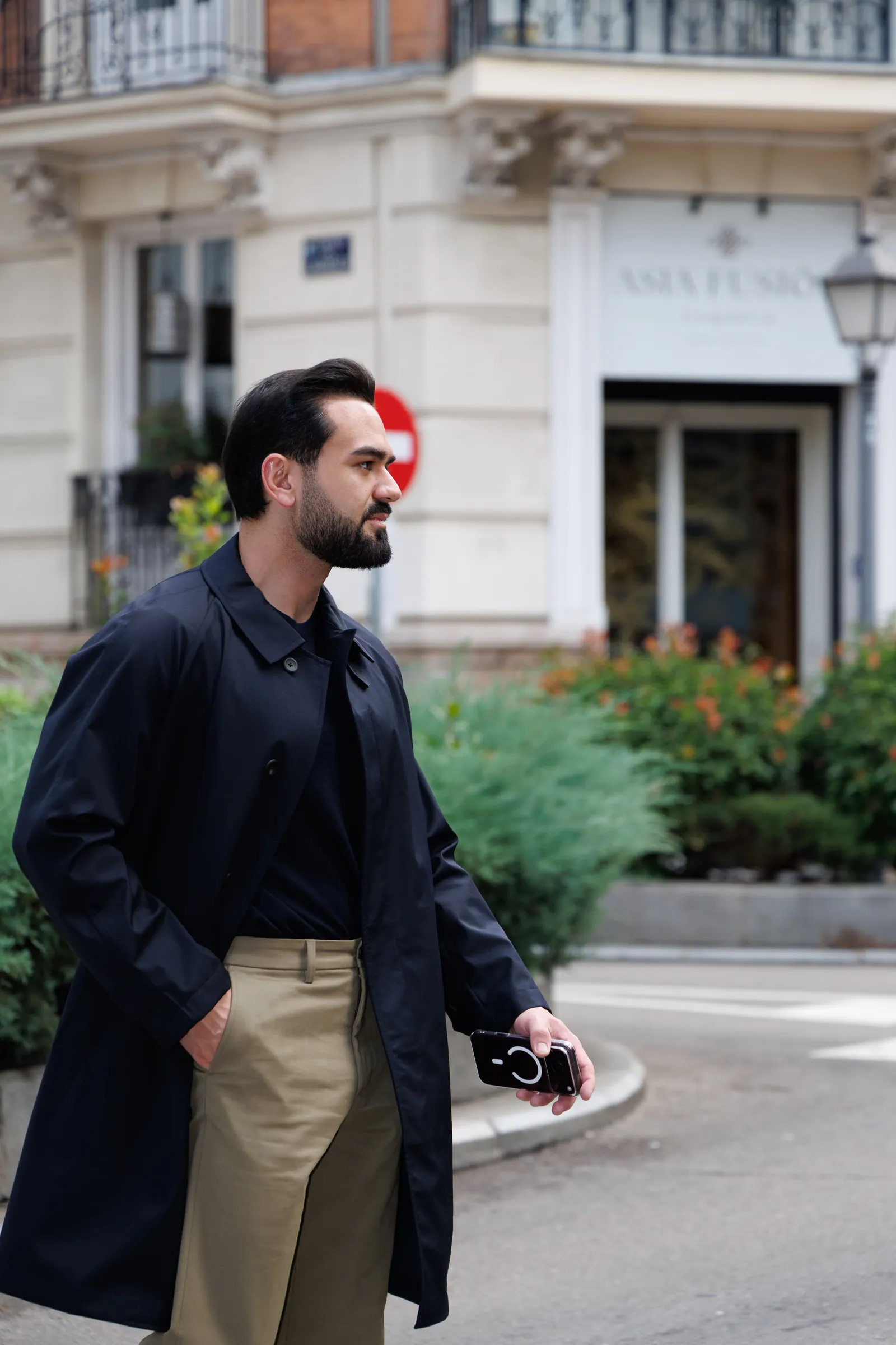 Man in a navy coat walking past classic Madrid apartment buildings