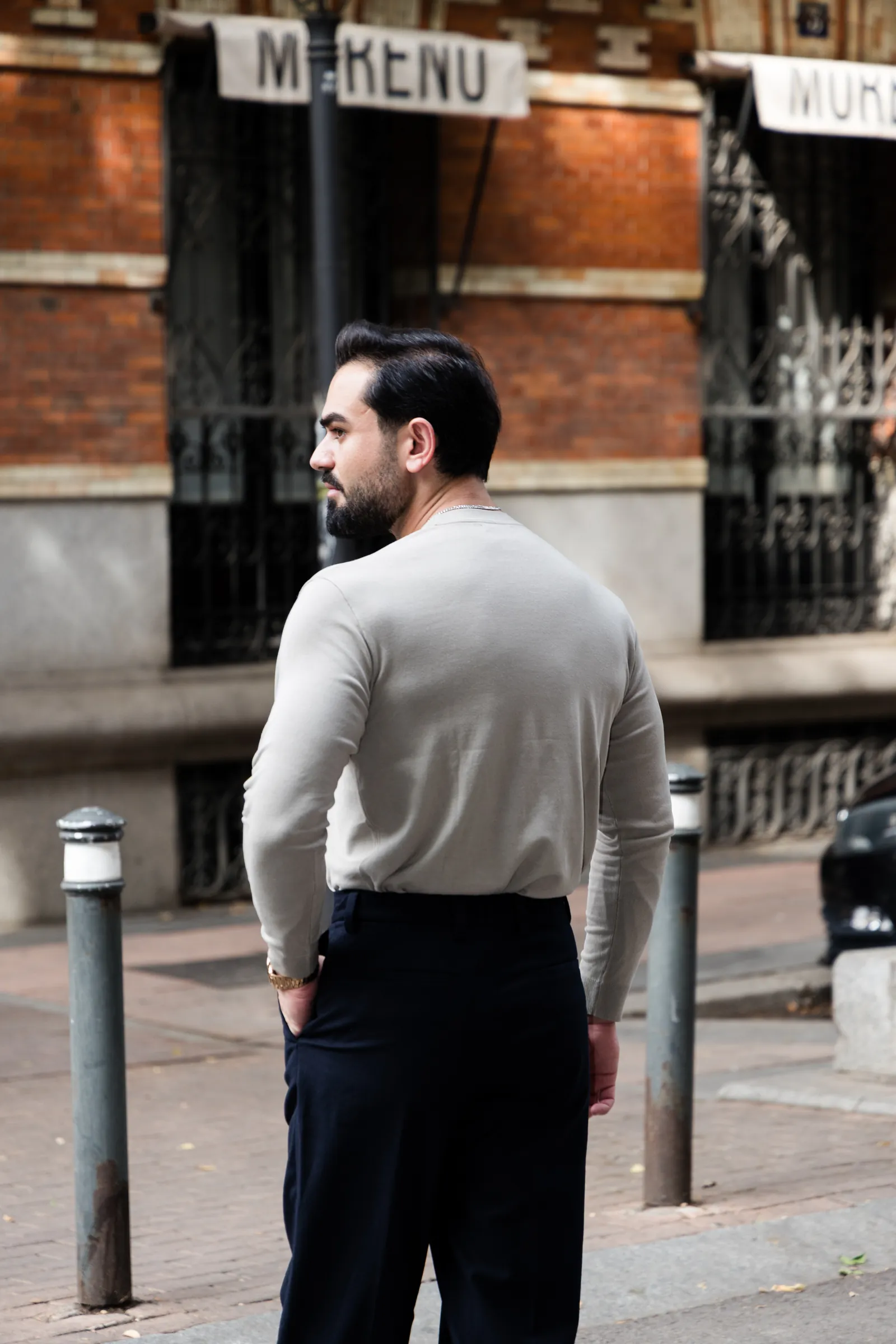 Man in a light knit seen from behind in profile on a Madrid side street