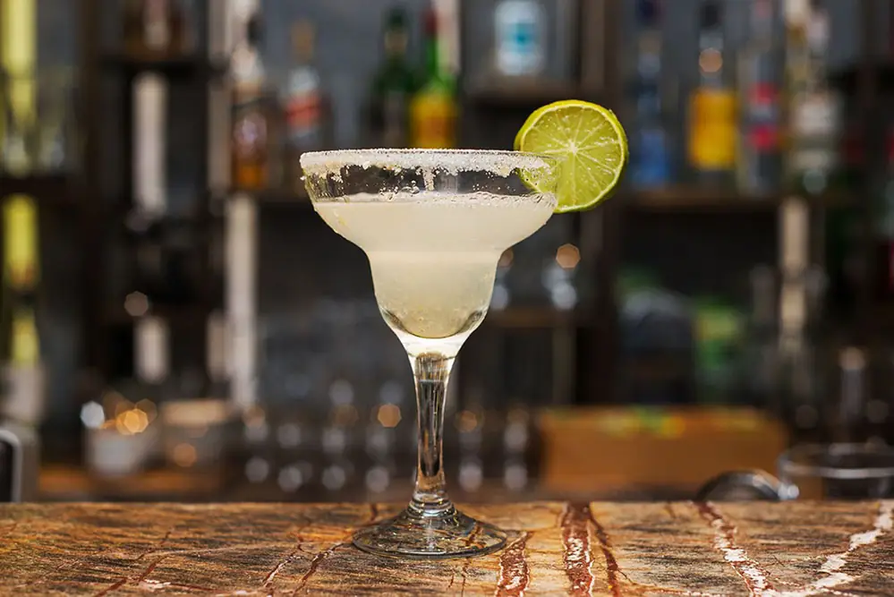 Margarita with a salted rim standing on a wooden bar
