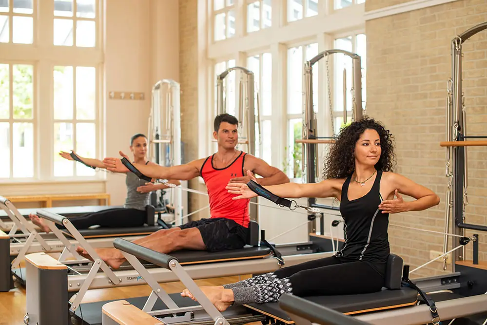 Group pilates class working on reformers in a daylit studio
