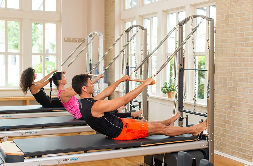 Two people mid exercise on reformers during a pilates session