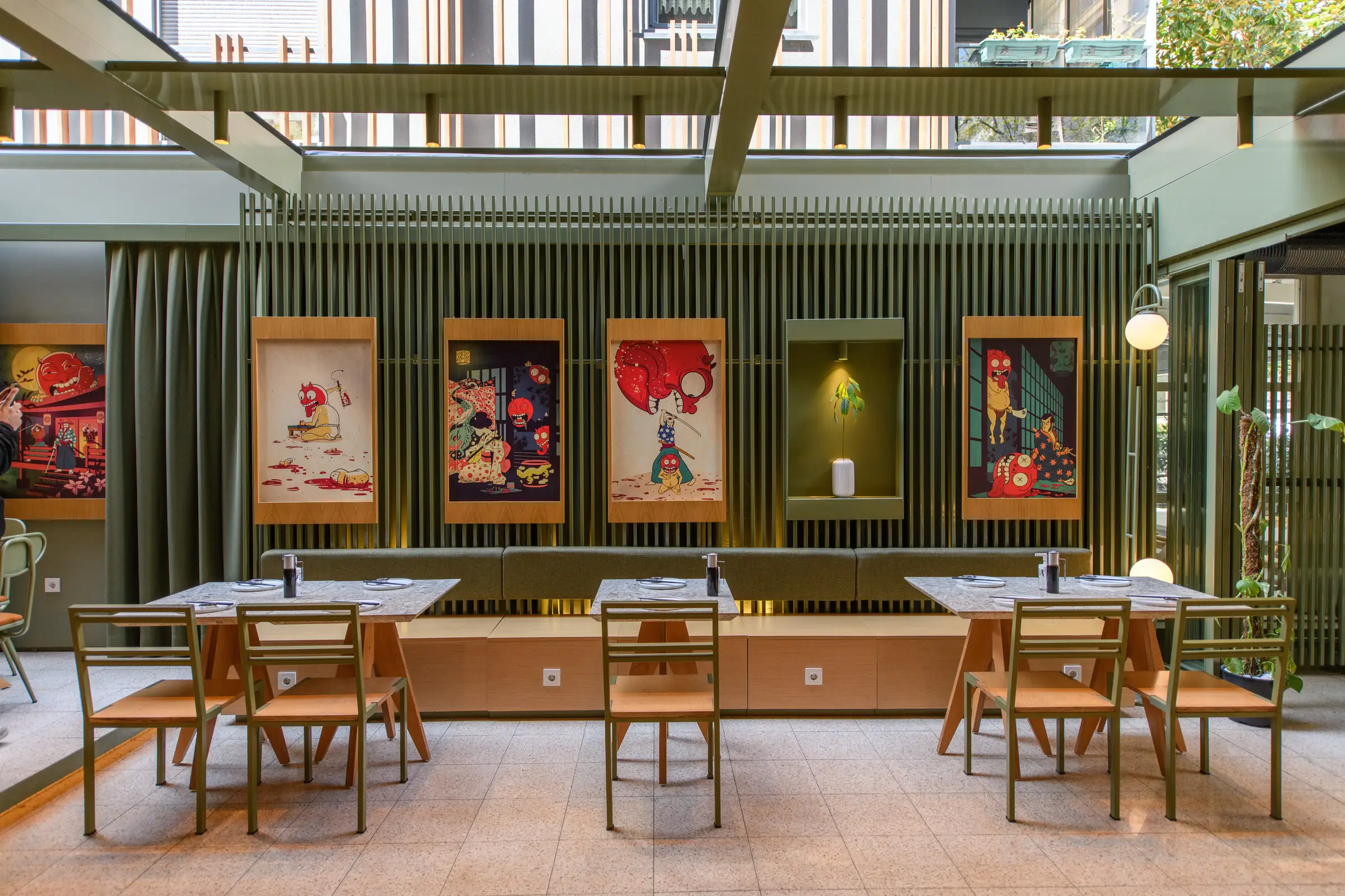 Restaurant dining room with framed prints along a green slatted wall