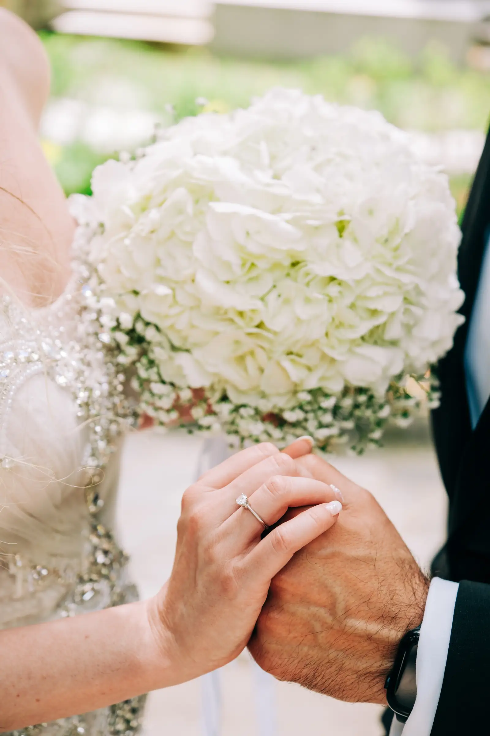 Close view of the couple's hands and wedding ring resting on the bridal bouquet