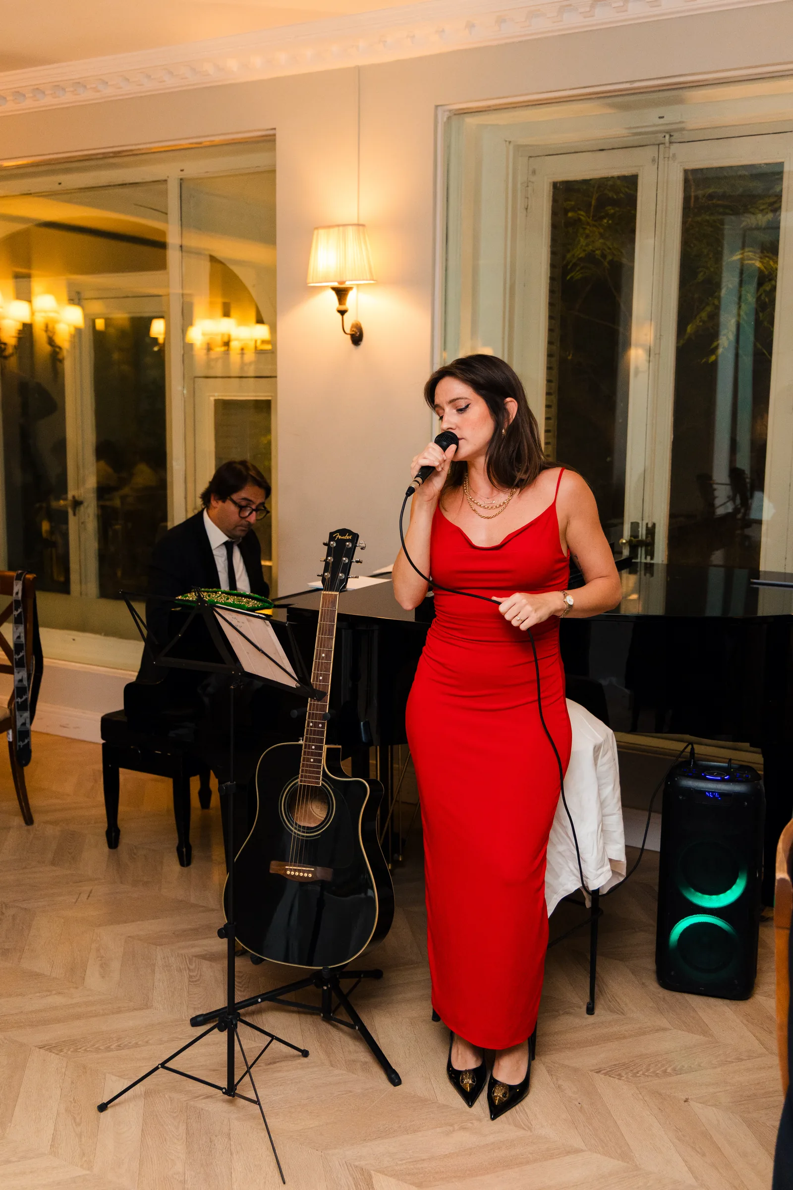 A singer in a red dress performing beside the pianist