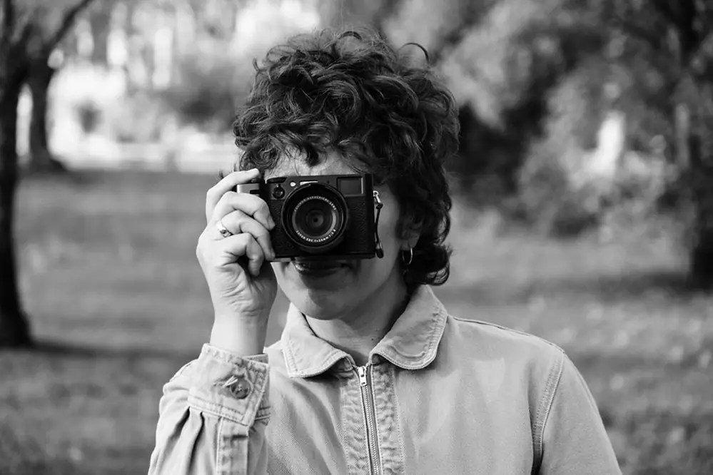 Srdana photographing with a rangefinder camera in a park, black and white