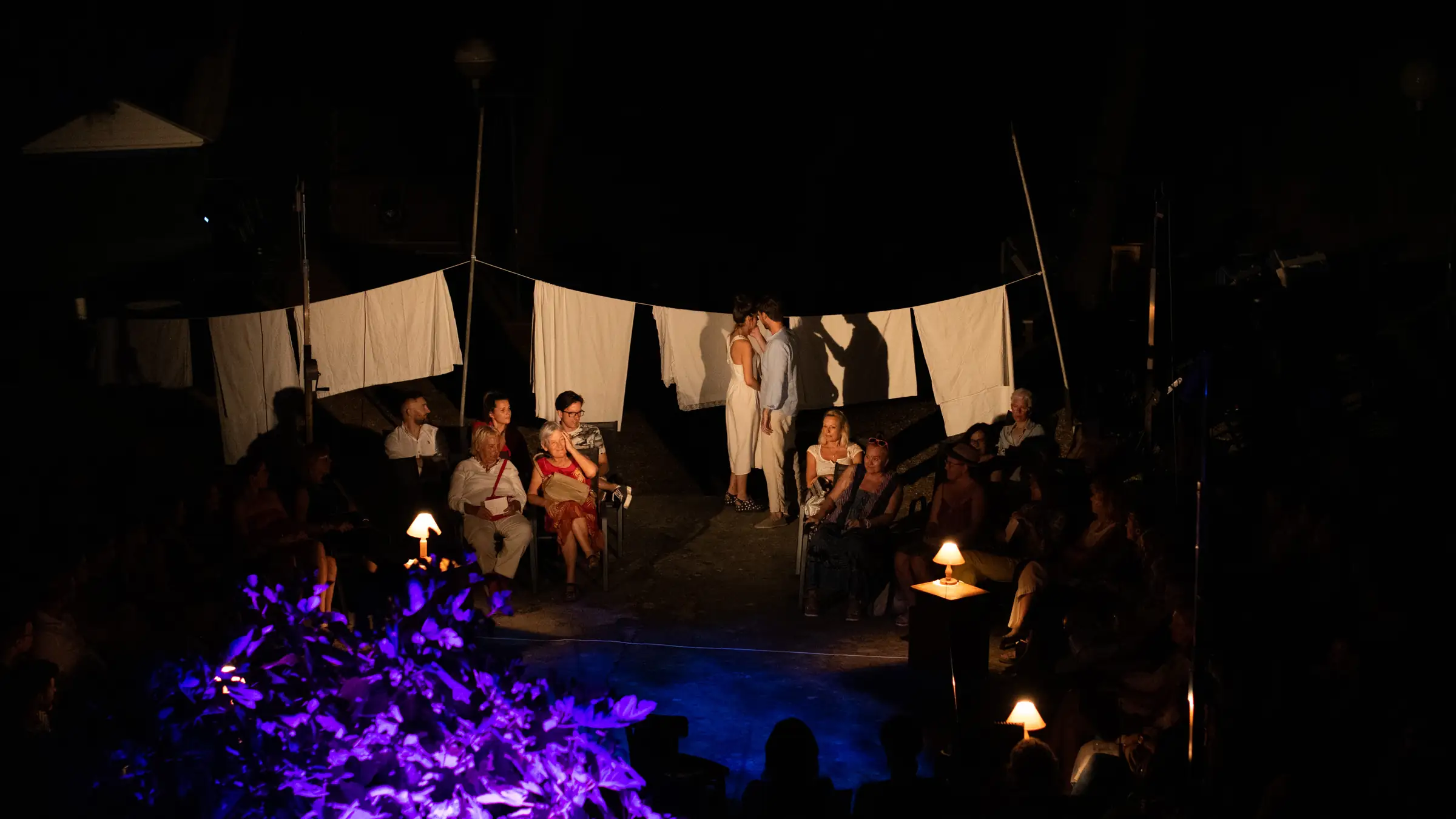 Cast holding a white cloth across the stage during a night performance