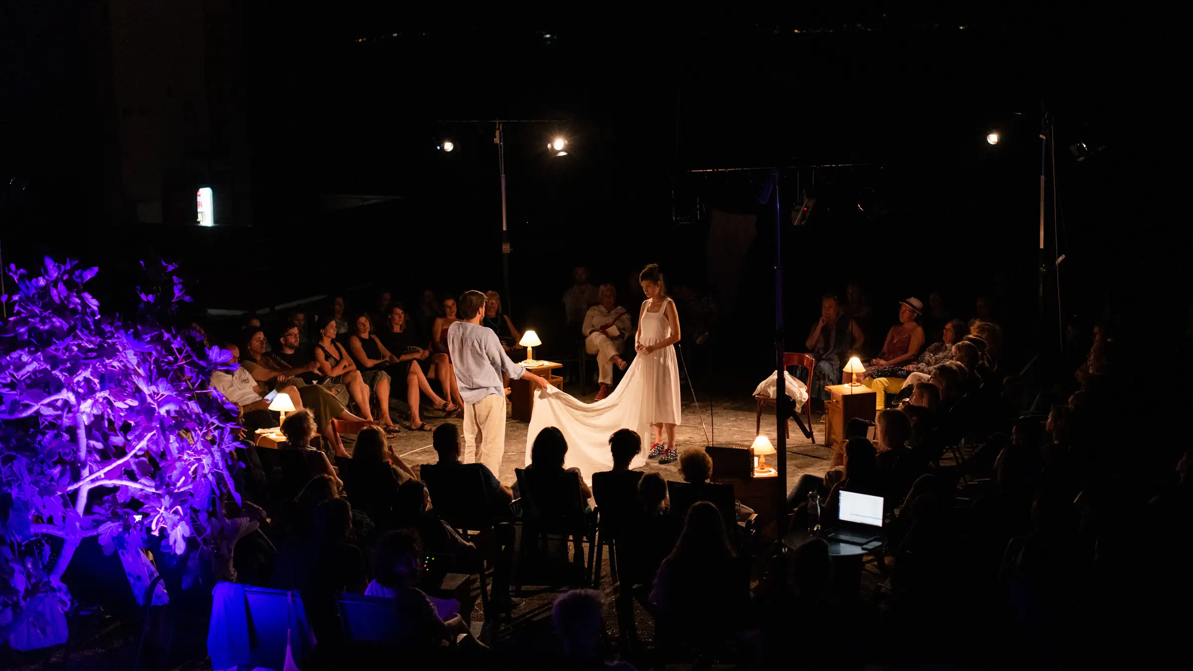 Performers stretching a white cloth in front of a seated audience