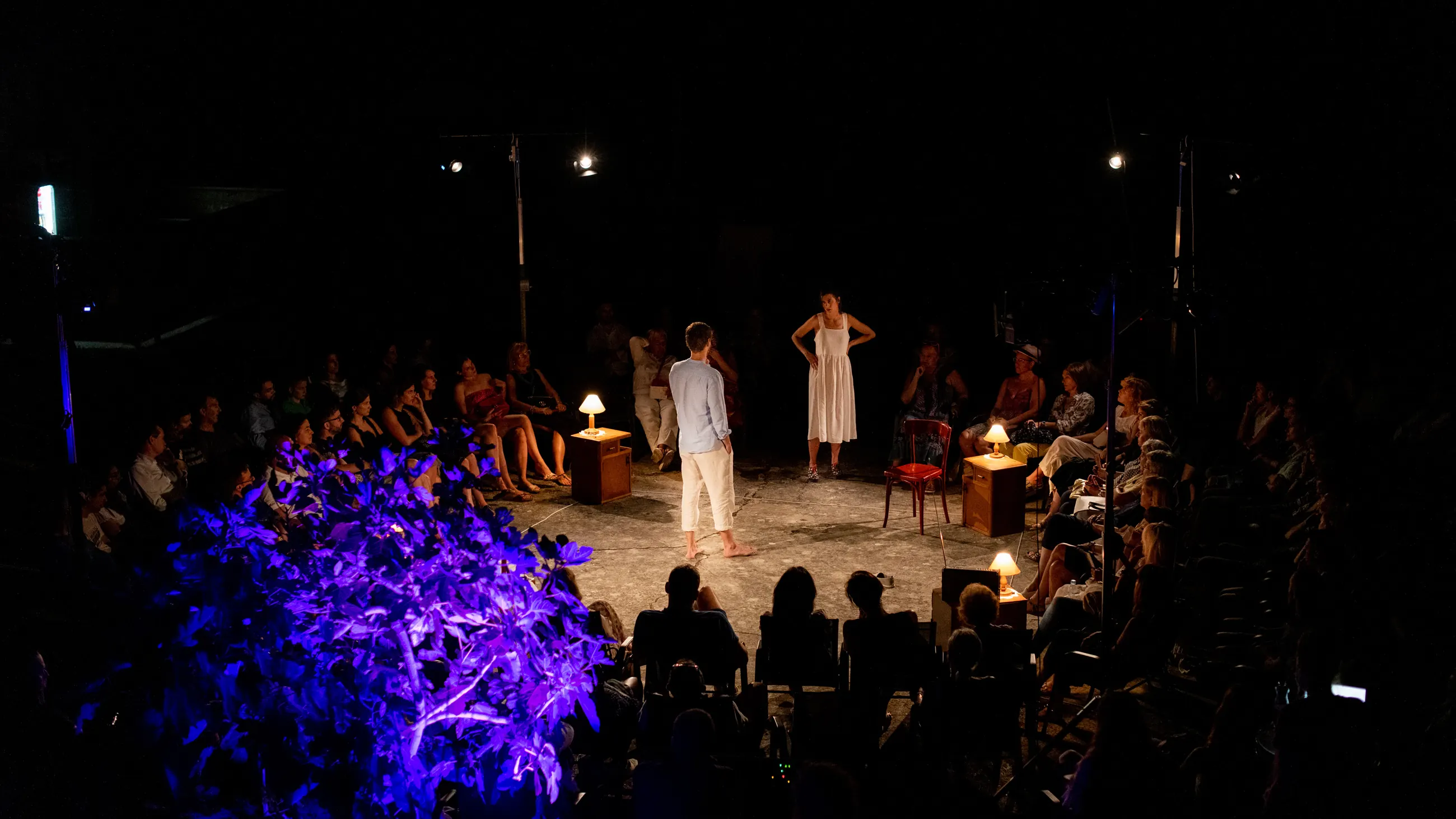 Wide view of an open air stage lit in the round at night