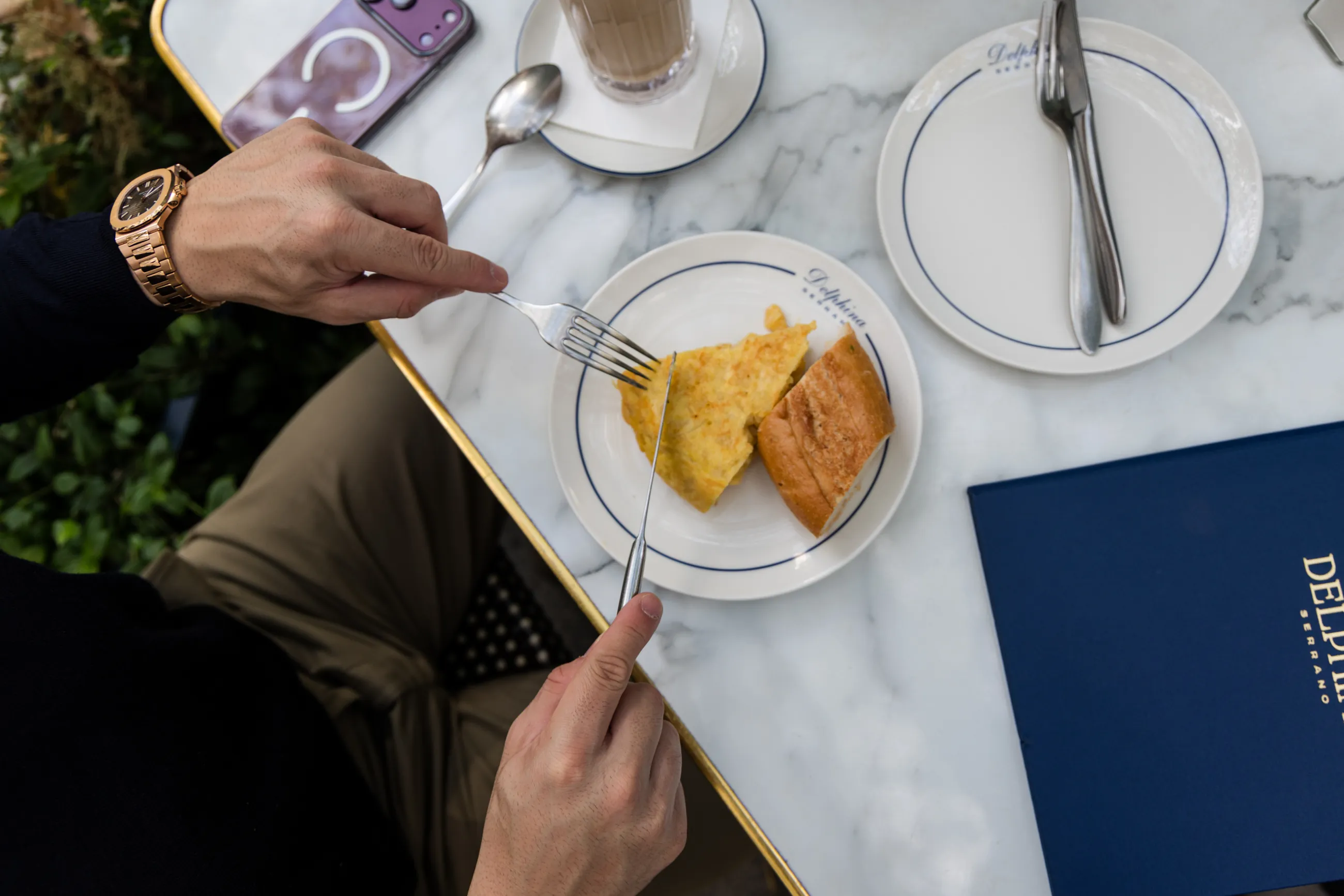 From above: a slice of tortilla, bread and a coffee on a marble café table